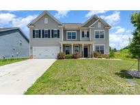 Charming two-story home boasts a manicured lawn, inviting entrance, and a two-car garage at 10045 Carousel Corral Dr, Midland, NC 28107
