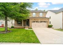 Charming two-story brick home with a covered front porch and attached two-car garage at 12923 Plumleaf Dr, Charlotte, NC 28213