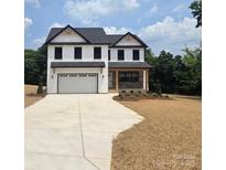 Charming two-story home featuring white siding, black trim, an attached garage, and a covered front porch with stone accents at 1308 Austin Chaney Rd, Wingate, NC 28174