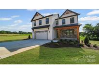 New two-story home with white siding, stone accents, covered entry, large driveway, and manicured lawn at 1308 Austin Chaney Rd, Wingate, NC 28174