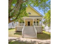 Charming yellow two-story home featuring a welcoming front porch and well-maintained yard at 14105 Garden District Row, Huntersville, NC 28078
