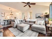 Spacious living room featuring a plush gray sectional, elegant area rug, and a modern ceiling fan at 18605 Ruffner Dr # 3E, Cornelius, NC 28031