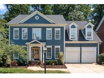 Beautiful two-story blue home featuring an attached two car garage, manicured lawn, and tasteful landscaping at 20324 Middletown Rd, Cornelius, NC 28031