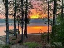 Scenic waterfront view at sunset with a private dock and tranquil lake reflecting the warm colors at 258 Patterson'S Bridge None, New London, NC 28127