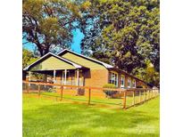 Charming single-story brick home featuring a covered porch, fenced yard, and lush greenery, providing a cozy and inviting atmosphere at 300 N Watterson St, Kings Mountain, NC 28086