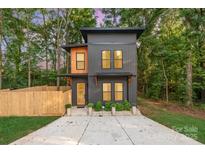 Modern two-story home featuring a gray facade, natural wood accents, and a charming fenced yard at 411 Granby Cir, Charlotte, NC 28217