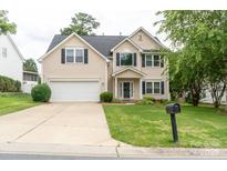 Charming two-story home with a well-manicured lawn and attached garage, painted in neutral beige at 435 Riverwalk Nw Dv, Concord, NC 28027