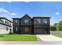 Stunning modern home showcasing a bold black facade with wood accents and manicured landscaping at 5432 Carmel Rd, Charlotte, NC 28210