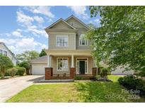Charming two-story home with a welcoming front porch, well-maintained lawn, and an attached garage at 7642 Rolling Meadows Ln, Huntersville, NC 28078