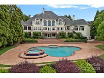 Beautiful backyard pool and spa with brick surround and lush landscaping, perfect for entertaining at 8800 Covey Rise Ct, Charlotte, NC 28226