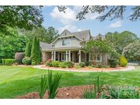 Charming home featuring a well-maintained lawn, mature trees, and inviting front porch with classic design elements at 9202 Arlington Hills Dr, Mint Hill, NC 28227