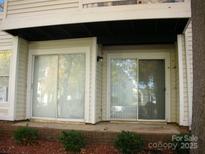 A condo's back patio with two sliding glass doors and a small brick patio lined with greenery at 9603 Vinca Cir # A, Charlotte, NC 28213