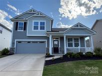 Charming two-story home with gray siding, stone accents, a covered porch, and a two-car garage at 1016 Laggan Ln, Indian Trail, NC 28079