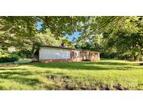Quaint brick home on a large lot, shaded by mature trees and green grass at 1229 Rocky Face Church Rd, Taylorsville, NC 28681