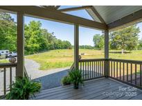 Inviting covered porch offers scenic views of the surrounding green pasture and countryside at 16132 Mclester Rd, Oakboro, NC 28129