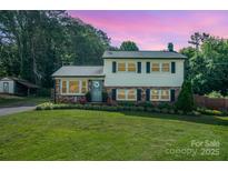 Charming two-story home with well-manicured lawn, brick accents, and lush landscaping creating curb appeal at 205 Wingate Dr, Stanley, NC 28164