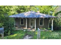 Charming single-story home with front porch, nestled amidst lush greenery and mature trees at 210 Mahan Sw St, Concord, NC 28025