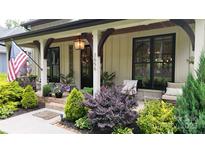 Inviting front porch with beautiful landscaping and craftsman style pillars and warm pendant lighting at 2656 Lee Lawing Rd, Lincolnton, NC 28092