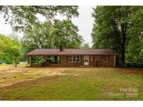 Charming brick home with a covered porch, nestled among mature trees, offers a serene and inviting curb appeal at 661 Blackwelder Rd, Statesville, NC 28625