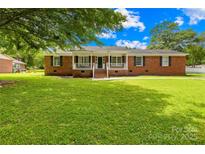 Charming red brick home with a welcoming front porch and large, well-manicured lawn at 815 Lakeside Cir, Lancaster, SC 29720