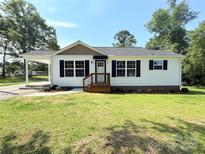 Charming single-story home featuring a well-maintained front lawn, covered carport, and classic black shutters at 111 W Perry St, Heath Springs, SC 29058