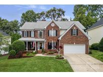 Charming two-story brick home with a manicured lawn and attached two-car garage at 11917 Ulsten Ln, Huntersville, NC 28078