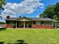 Charming single-story brick home featuring a cozy front porch, lush green lawn, and mature trees at 1585 Salem Church Rd, Lincolnton, NC 28092