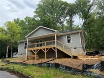 New construction home featuring gray siding, a covered porch, and wooden stairs leading to the front entrance at 32874 Old Salisbury Rd, Albemarle, NC 28001