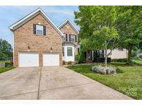 Charming brick home featuring an attached two-car garage and a well-manicured front yard with mature trees at 4392 Sunset Rose Dr, Fort Mill, SC 29708