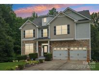 Charming two-story home featuring a stone facade, attached garage, and beautifully landscaped front yard at 5021 Meadow Woods Dr, Lowell, NC 28098