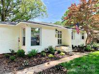Charming white brick home with an American flag and lush landscaping at 5033 Baylor Dr, Charlotte, NC 28210