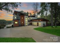 Stunning modern home featuring a spacious driveway, three-car garage, and picturesque lake views at 5930 Midsomer Rd, Charlotte, NC 28214