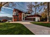 Stunning lakefront home with modern design, stone accents, and a spacious driveway at 5930 Midsomer Rd, Charlotte, NC 28214