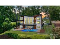 Stunning modern home featuring a private pool and deck, complemented by expansive windows and lush landscaping at 5930 Midsomer Rd, Charlotte, NC 28214