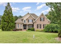 Charming brick home featuring a manicured lawn, lush landscaping, and a classic architectural design at 6057 Erie View Ct, Denver, NC 28037