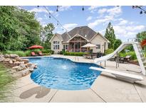 Inviting backyard pool featuring a diving board, slide, waterfall feature, and ample seating for outdoor relaxation and entertaining at 6057 Erie View Ct, Denver, NC 28037