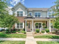 Charming townhome with a brick and siding facade, a manicured lawn, and a welcoming pink front door at 9405 Gladden Hill Ln, Pineville, NC 28134