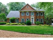 Traditional two-story brick home featuring a manicured front lawn and mature landscaping at 9901 Pallisers Ter, Charlotte, NC 28210