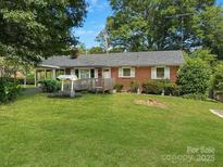 Charming single-story brick home featuring a well, lush green lawn, and mature trees at 1008 Midway Dr, Gastonia, NC 28054