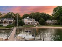 Stunning waterfront home with private dock, sandy beach, and mature trees under a colorful sky at 123 Sailview Rd, Mooresville, NC 28117