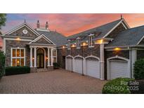 Stunning stone home with a brick driveway, a 4-car garage, and a beautiful sunset backdrop at 123 Sailview Rd, Mooresville, NC 28117