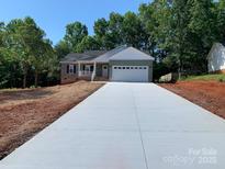 Charming one-story home featuring a two-car garage, green siding, and a long concrete driveway at 136 Ridge Run Dr, Statesville, NC 28625