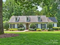 Charming single-story home with a manicured lawn, dormer windows and mature trees in a lush, green setting at 2919 Wickersham Rd, Charlotte, NC 28211