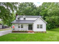 Charming renovated two-story home featuring a welcoming front porch, fresh landscaping, and white board and batten siding at 4633 Old Mill Rd, Gastonia, NC 28056