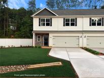 Charming two-story townhome with a manicured lawn, a two-car garage and stone details at 6712 W Sugar Creek Rd, Charlotte, NC 28269