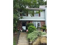 Charming townhouse with brick facade and inviting front entrance framed by lush landscaping and weathered wood retaining wall at 7304 Pebblestone Dr, Charlotte, NC 28212