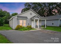 Charming single-story home with covered porch, cozy seating, neat landscaping, and a freshly paved driveway at 204 Craig St, Mount Holly, NC 28120