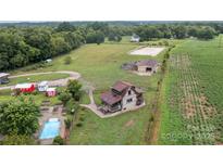 Aerial view of a home with a pool, barns, white horse training ring, and agricultural fields at 2310 Gill Jordan Rd, Chester, SC 29706