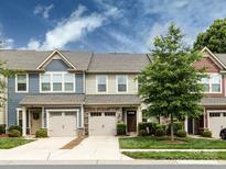 Charming townhome featuring stone accents, a driveway, and manicured landscaping under a partly cloudy sky at 403 Park Meadows Dr, Matthews, NC 28104