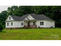 Charming one-story home featuring white siding, a welcoming front porch, and a lush green lawn with beautiful surrounding trees at 4710 Old Pageland Marshville Rd, Monroe, NC 28112